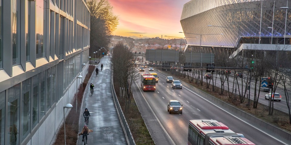Cyklister som cyklar på cykelbanan och bilar som kör på bilvägen, Nynäsvägen. Foto.