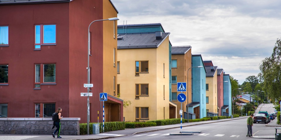 Färgglada hus längs en bilväg.