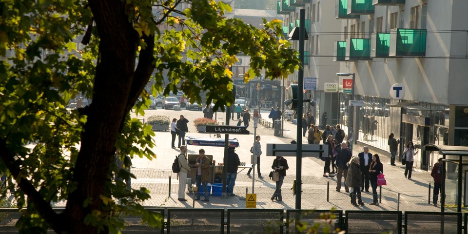 Människor i rörselse och några som väntar på tvärbanan vid Liljeholmen.