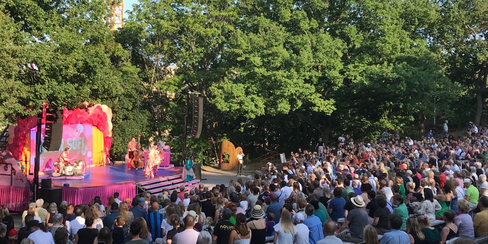 En rosa utomhusscen med stor publik en sommardag.