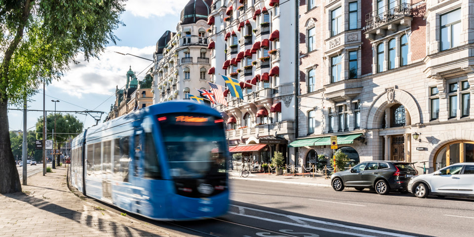 Spårvagnen far fram längs Strandvägen, Östermalm. Hus syns längs gatan.