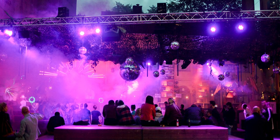 Människor sitter och samtalar och dansar på nattklubb Trädgården. Foto.
