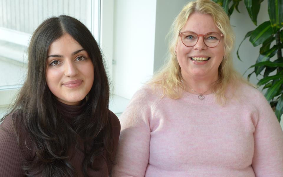 Två kvinnor som tittar in i kameran och ler, halvporträtt, fotografisk bild