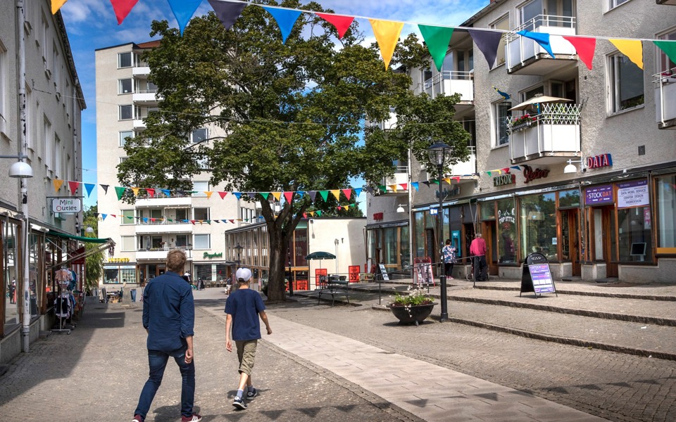 Hökarängens centrum med färgglada vimplar som hänger mellan husen. 