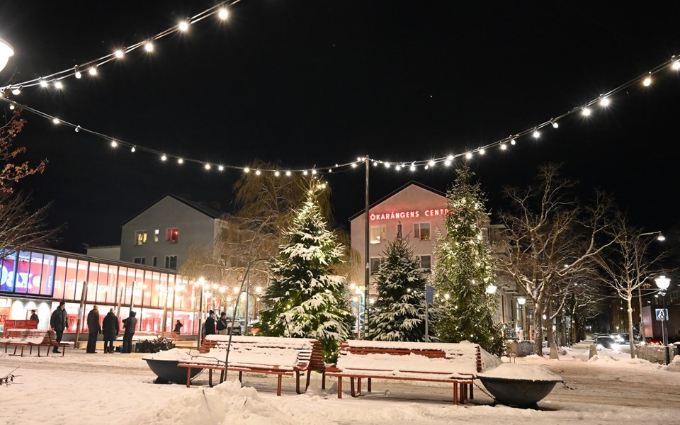 Ett snötäckt torg utanför Hökarängens centrum  som har fotograferats på kvällen.