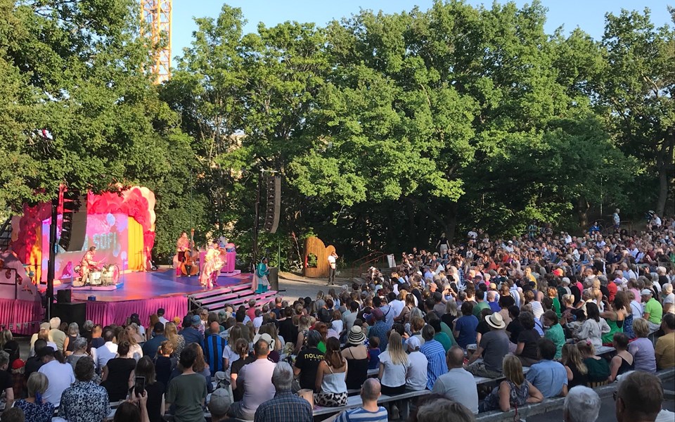 En rosa utomhusscen med stor publik en sommardag.