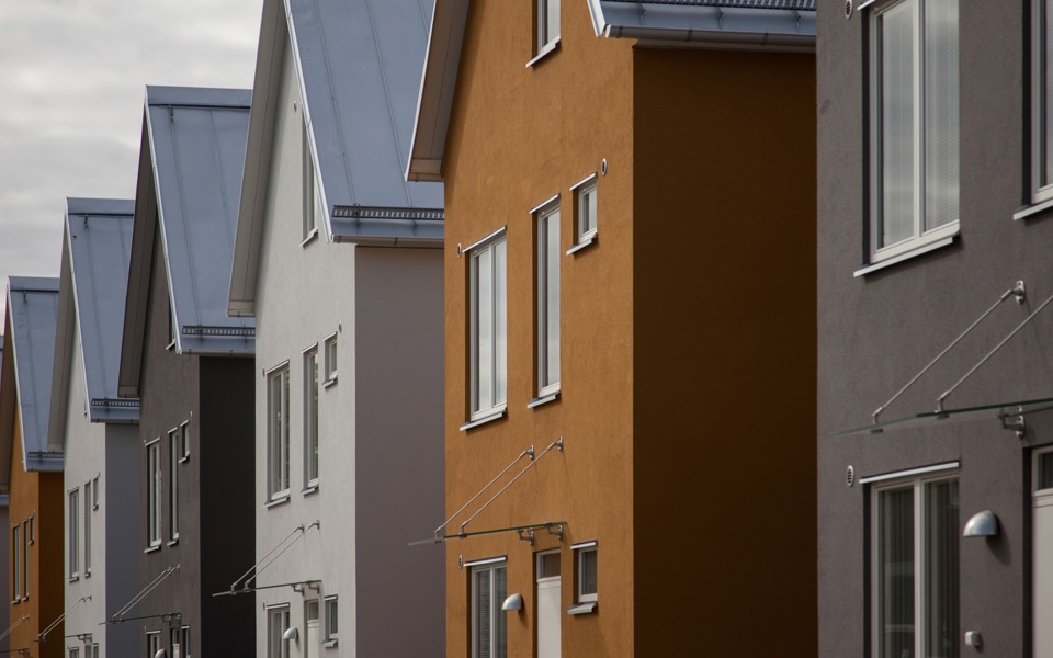 Flera likadana husfasader i jordnära färger och med sadeltak.