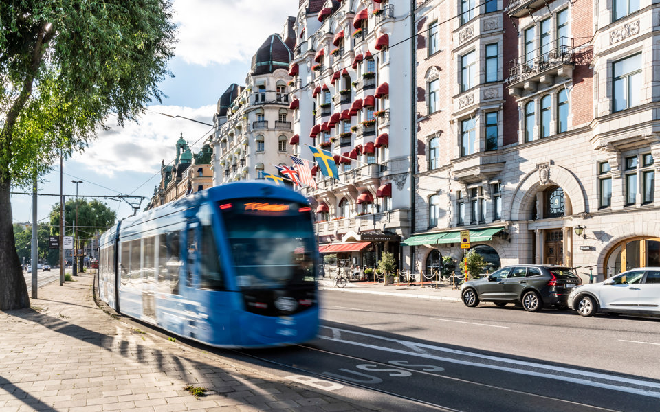 Spårvagnen far fram längs Strandvägen, Östermalm. Hus syns längs gatan.