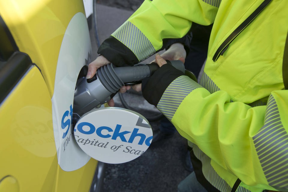 Händer som laddar en elbil.